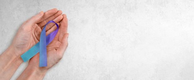 Teal and Purple Ribbon in Woman's Hands Suicide Prevention Awareness Concept with Copy Space