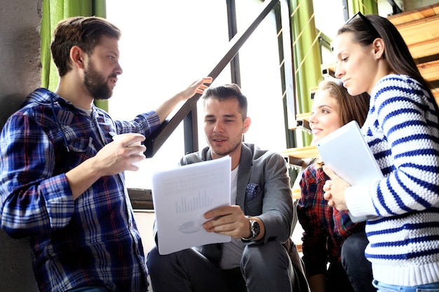 Team account manager project work.Photo business managers working with new startup in modern loft.Analyze reports,plans. Notebook on wood table, papers, documents, statistics. Horizontal, blurred