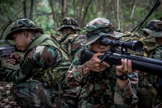 Team of army soldier with machine gun moving in the forestThai militia soldier in combat uniforms in the woodWander the patrol sloping in the rainforest