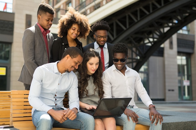 team of beautiful african people on bench with laptop in summer