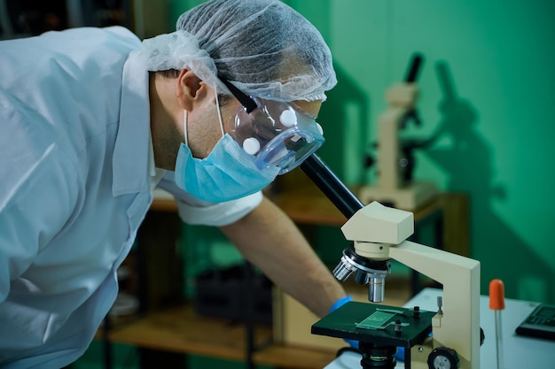 A team of biochemical research scientists work with a microscope to develop a vaccine against coronavirus in a drug research laboratory focus education concept