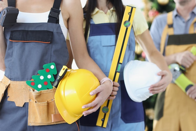 Team of builders with a tool and helmet on background of new year tree christmas and