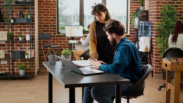 Team of business people analyzing email information to plan\
report, using data on documents and laptop. man and woman working\
with charts to create project analysis and send email.