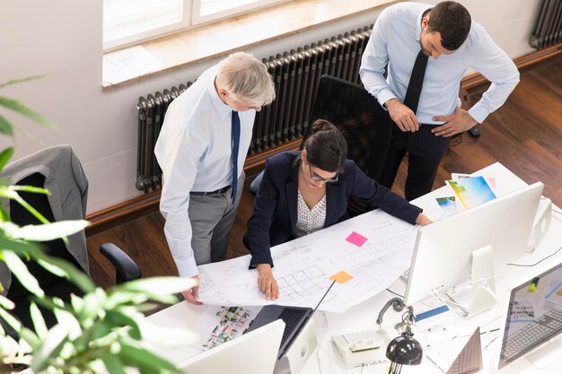 Team of business people in planning office working on blue print