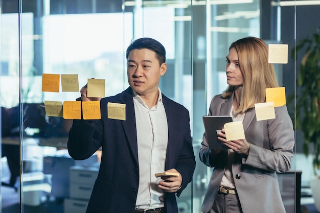 Team of business workers develop a business strategy and develop a plan an Asian man smiles at a female companion