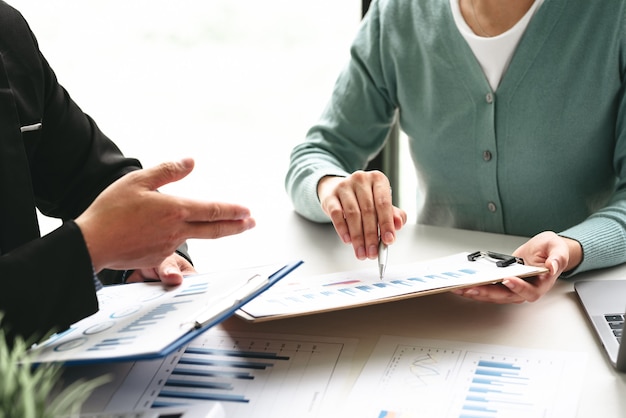 Team of businessman sitting together in the office brainstorming meeting holding a pen pointing at the graph at the office.