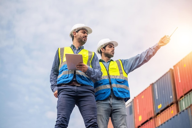 Team businessman working on site containers yard for business\
shipping import and export caucasian worker inspecting container in\
warehouse logistic delivery services export management team