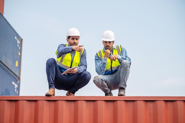 Team businessman working on site containers yard for business\
shipping import and export caucasian worker inspecting container in\
warehouse logistic delivery services export management team