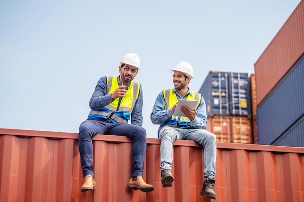 Team businessman working on site containers yard for business\
shipping import and export caucasian worker inspecting container in\
warehouse logistic delivery services export management team