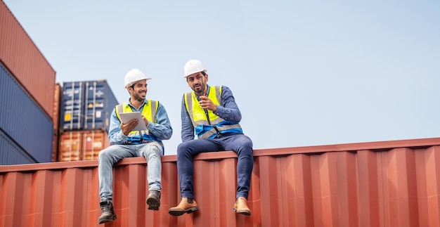 Team businessman working on site containers yard for business\
shipping import and export caucasian worker inspecting container in\
warehouse logistic delivery services export management team