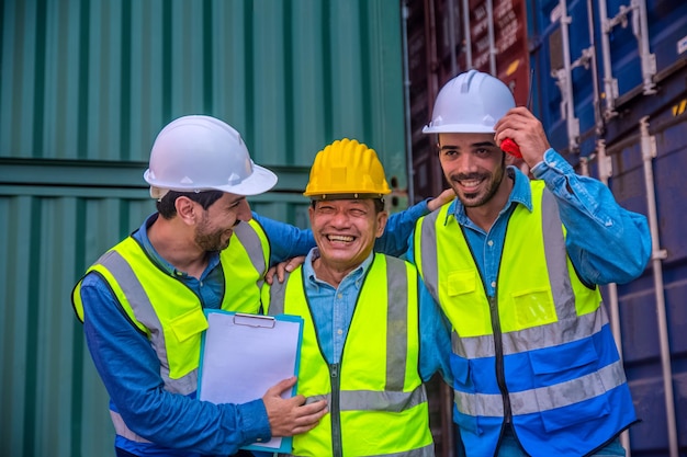 Team businessman working on site containers yard for business\
shipping import and export caucasian worker inspecting container in\
warehouse logistic delivery services export management team