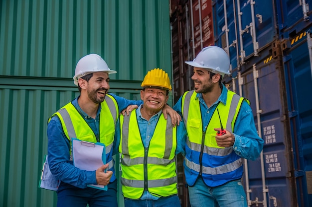 Team businessman working on site containers yard for business\
shipping import and export caucasian worker inspecting container in\
warehouse logistic delivery services export management team