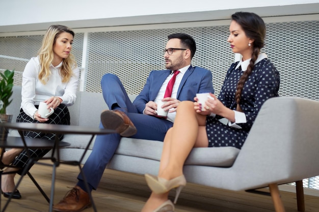 A team of businesspeople is sitting on a couch.