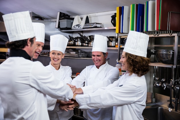 Team of chefs putting hands together and cheering