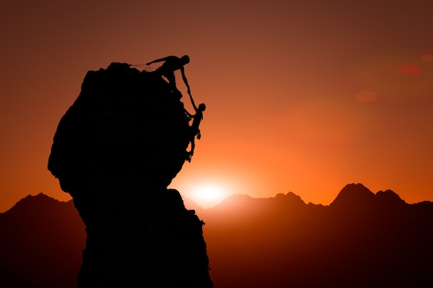 Team of climbers help to conquer the summit at sunset