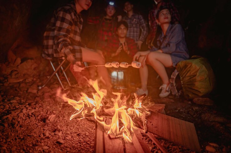 Photo 登山者の男性と女性のハイカーキャンプのチーム。彼らは洞窟のファイヤーキャンプの周りに座っています。ハイキング、ハイカー、チーム、山、洞窟、アクティビティのコンセプト。