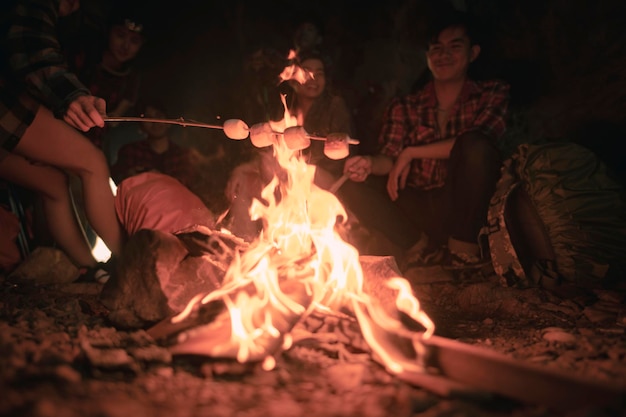 Team of climbers man and woman hiker camping.They are sitting around fire camp in the cave. Hiking, hikers, team, mountain, cave, activity concept.