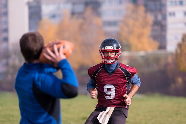 team coach throwing the ball into the group of young american football players in action during the training at the field