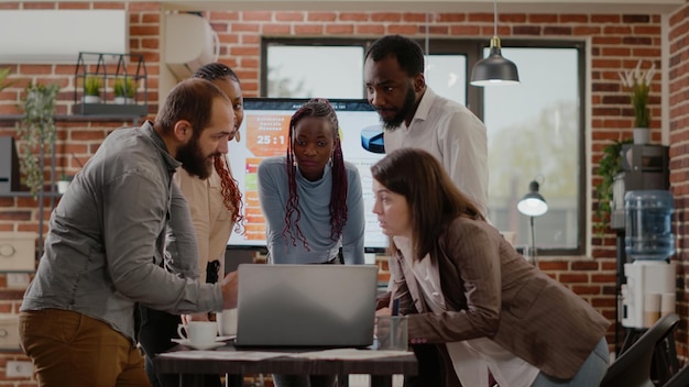 Team di colleghi che fanno brainstorming di idee per pianificare insieme progetti e strategie aziendali nell'ufficio di avvio. persone che lavorano alla progettazione e alla presentazione della strategia di marketing, guardando il laptop.