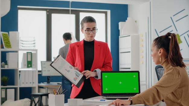 Team of coworkers using green screen on laptop to work on startup business. Women working with mock up template and isolated background on chroma key computer display in office.