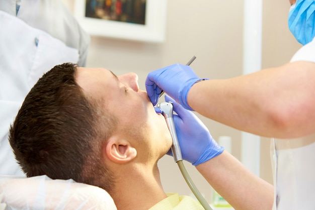 Team of dentists treats teeth to patient in dental clinic.