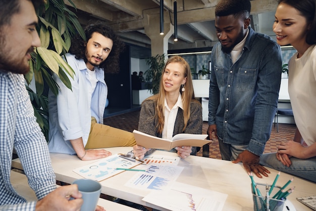 Photo team of diverse coworkers in modern office discuss their project together