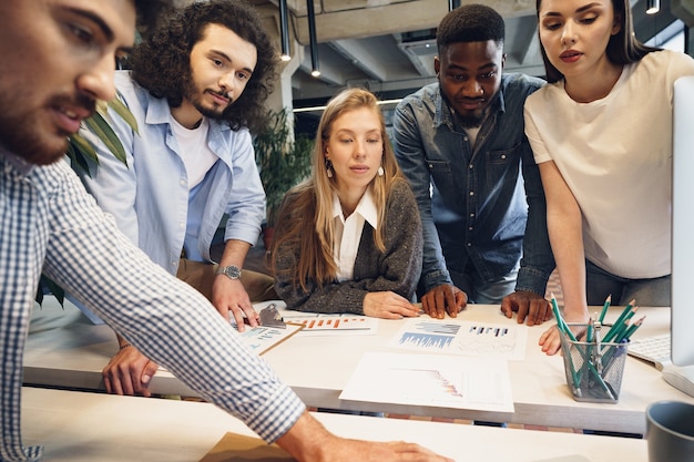 Il team di diversi colleghi in un ufficio moderno discute insieme il loro progetto