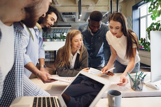 Team of diverse coworkers in modern office discuss their project together