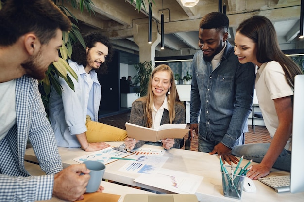 Team of diverse coworkers in modern office discuss their project together