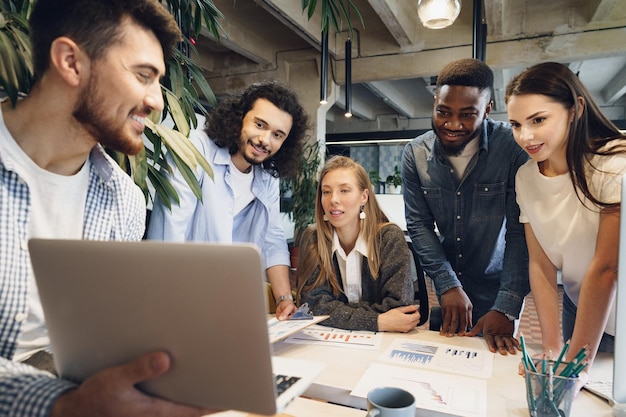 Team of diverse coworkers in modern office discuss their project together