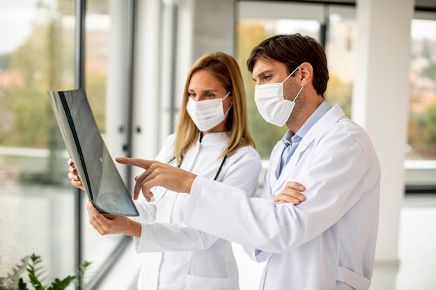 Team of doctors with protective facial masks examining xray in the office