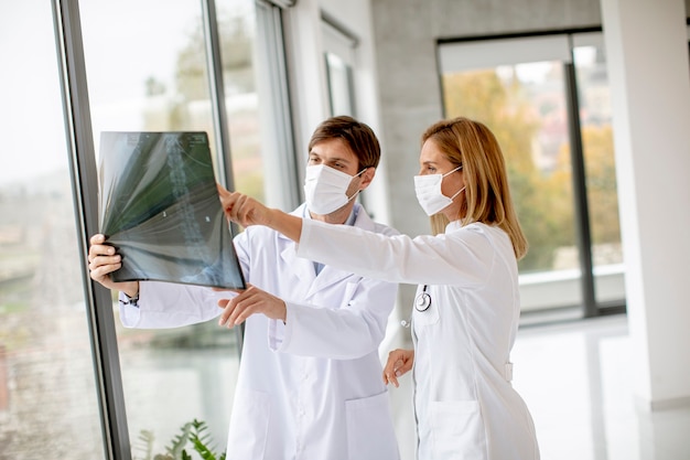 Team of doctors with protective facial masks examining xray in the office