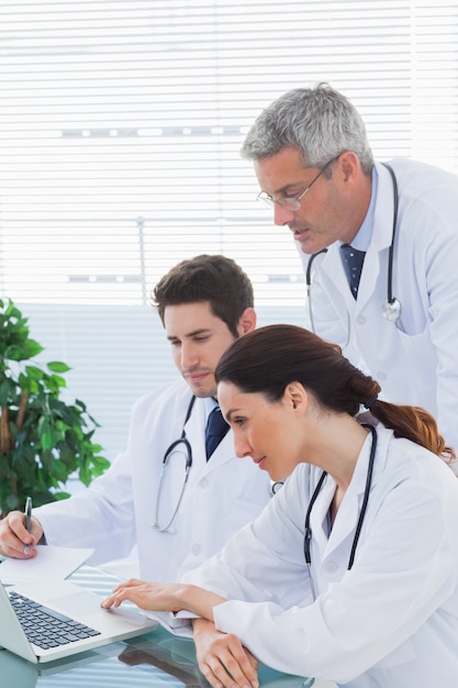 Team of doctors working together and watching something on their laptop