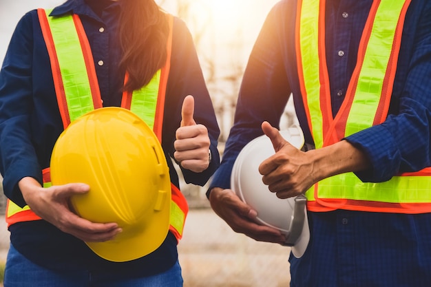 Team Engineer holding safety helmet on factory background