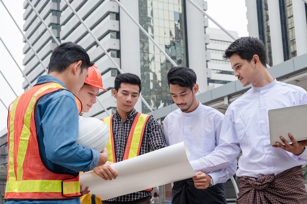 Team of engineer with myanmar businessman holding blueprint meeting and discussing of construction project at the city