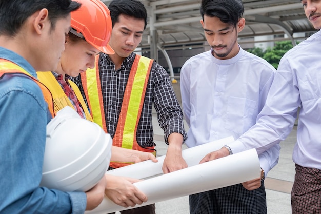 Team of engineer with myanmar businessman holding blueprint meeting and discussing of construction project at the city