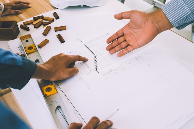 Team of engineers discussing architecture plan sketch at the construction site.