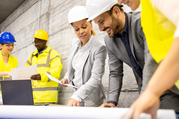 Team of experienced architects and civil engineers analyzing plans at construction site