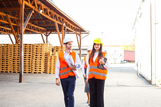 Team of expert architects on construciton site in helmets checking workflow