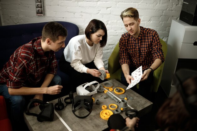 Team di quattro ingegneri creativi che lavorano con la realtà virtuale, giovane donna che prova occhiali o occhiali vr seduti nella stanza dell'ufficio