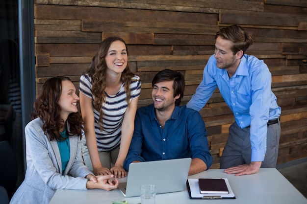 Squadra di grafici che sorridono mentre per mezzo del computer portatile