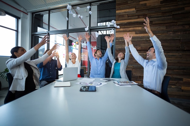 Team of graphic designers throwing paper ball up in air