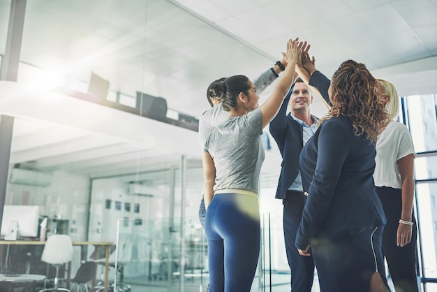 Team number one Successful group of business people giving a high five in support team building achievement Work colleagues celebrating good teamwork project together in modern conference office