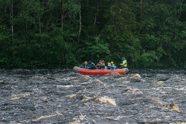 team op een vlot vlotten naar beneden een turbulente rivier met beboste oevers