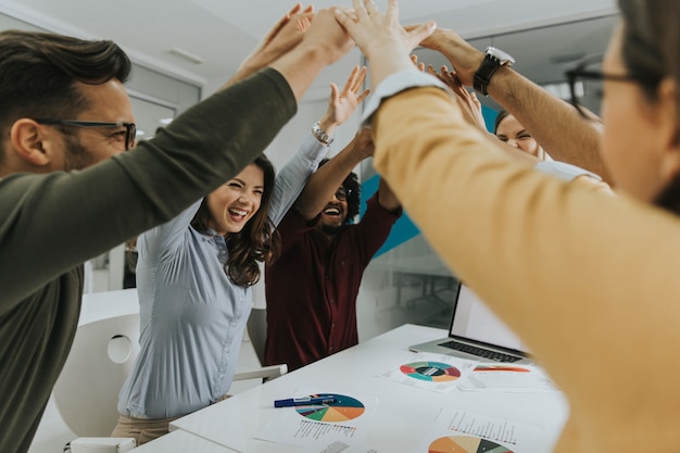 Team people stacking hands together over table engaged in teambuilding