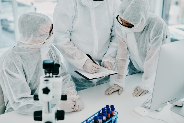 Team of scientists pathologists and doctors in hazmat suits discussing forensic research and plans in a lab Medical experts working on tests experiments and drug trial to develop cure for disease