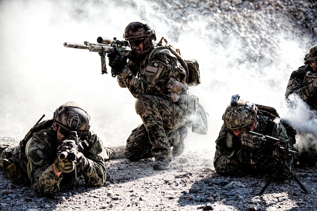 Team squad of special forces in action in the desert among the rocks covered by smoke screen