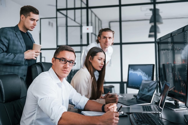 Team of stockbrokers works in modern office with many display screens