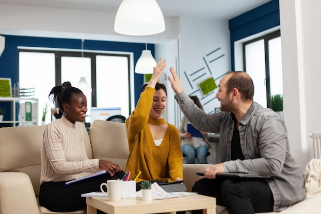 Photo team of successful young entrepreneurs sharing highfive celebrating success