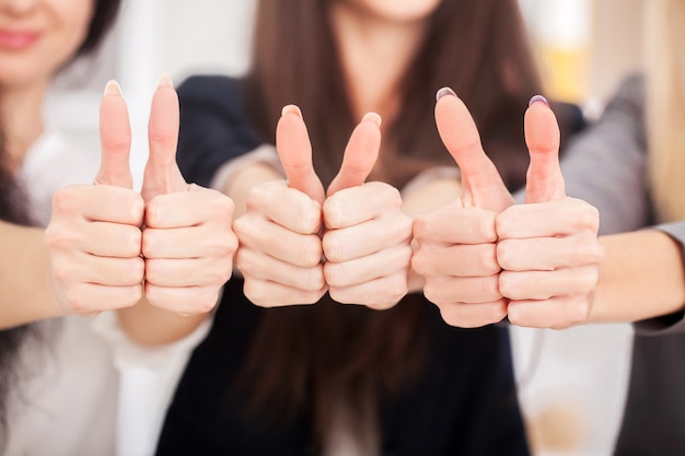 Team. Three business partners keeping thumbs up